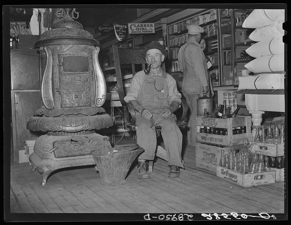 Farmer sits near the stove. General store. Lamoille, Iowa, 1939