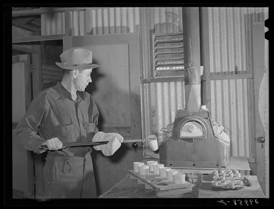 Assayer places crucible containing gold ore in furnace. El Dorado…, Nevada, 1940