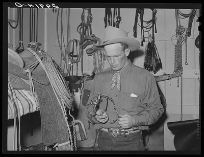 Cowhand examining bit. Capriola Saddlery, Elko, Nevada, 1940